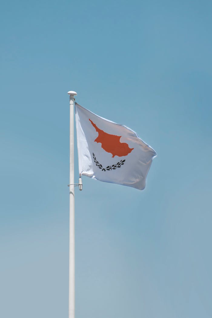 About The Cyprus national flag waving on a flagpole against a clear blue sky, showcasing patriotism.